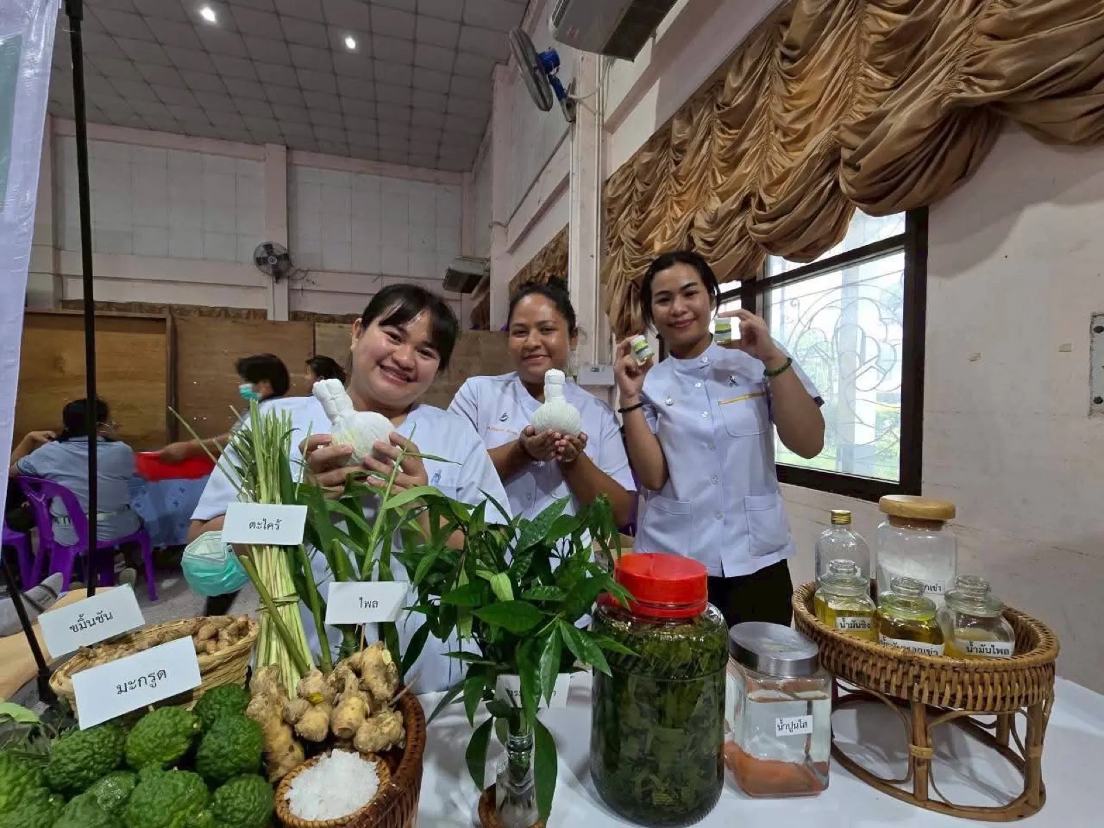 Demonstrating herbal compress balls with the fresh herbs they are made from