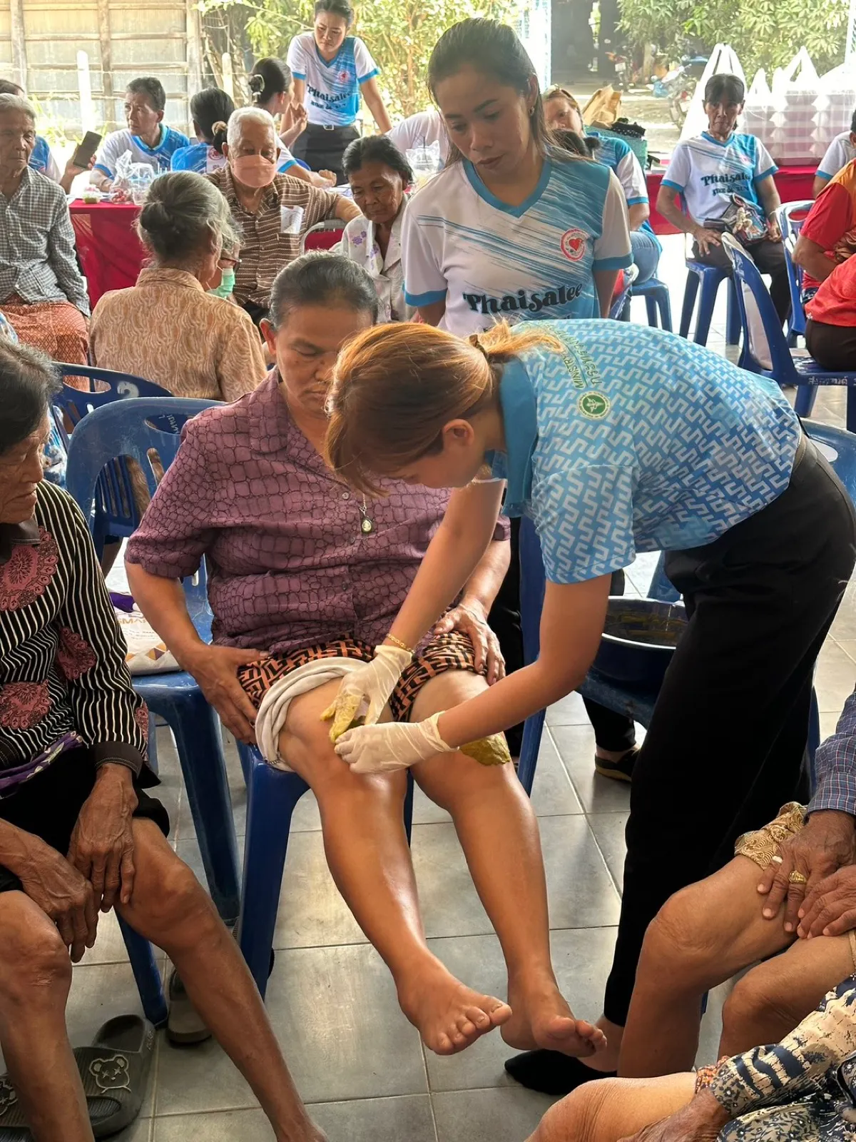 Applying a herbal knee poultice during a community clinic