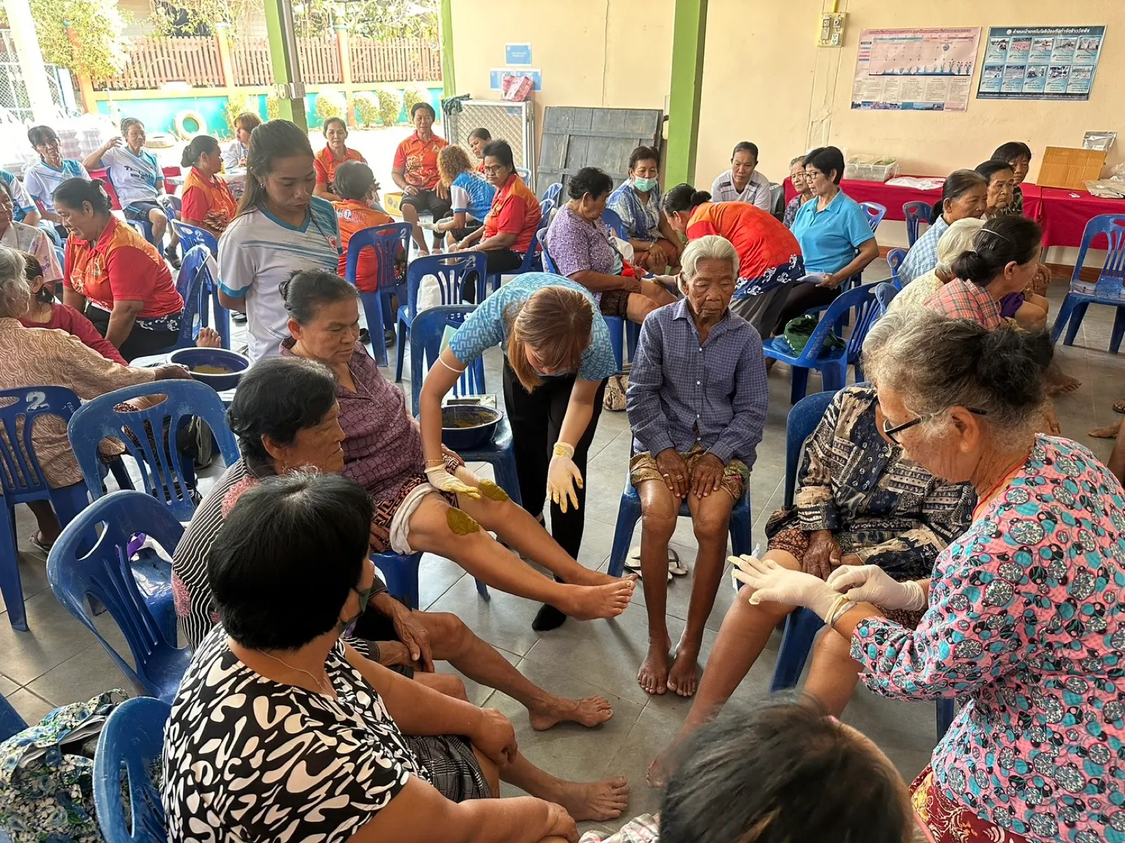 A community-hall clinic caring for a room of older residents
